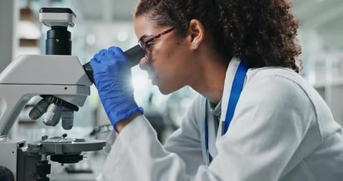 Woman Scientist Concentrating on Microscope Research in Lab