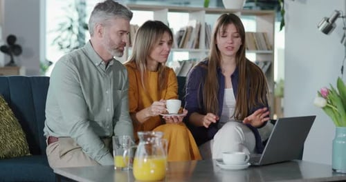 Three People Talking Indoors at a Laptop