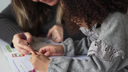 Girl Does Schoolwork with Helpful Adult