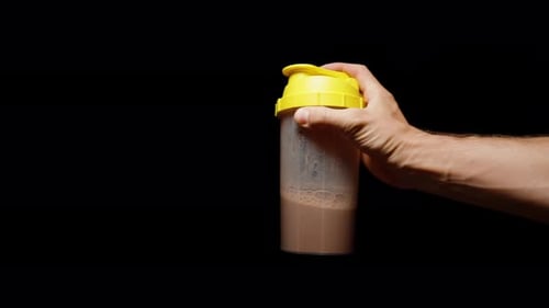 Hand Shaking Protein Drink Against Black Background