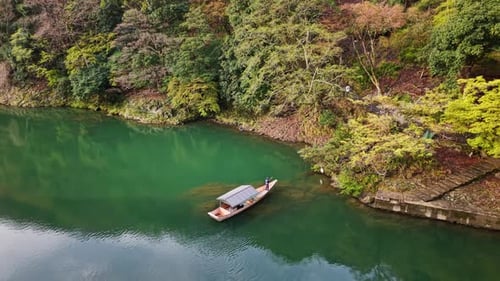 Drohnenaufnahme eines Bootes, das sich auf dem Katsura-Fluss in Arashiyama, Japan, bei Tageslicht bewegt