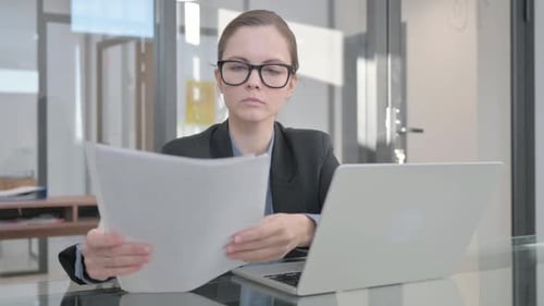 Woman Reviews Documents at Office Laptop