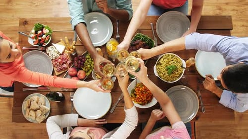 Friends toasting wine glasses at celebratory lunch together