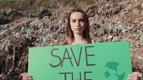 Woman Holding Save the Planet Sign near Landfill