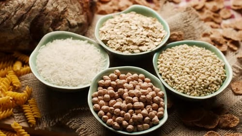 Various grains and carbohydrates in bowls on burlap