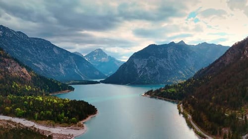 Grey cloudscape gathered in the sky reflects in the surface of Plansee Lake.