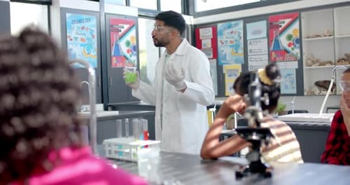 In a school chemistry lab, a biracial teacher engages young students