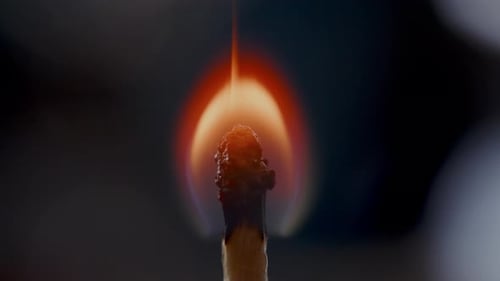 Nahaufnahme eines brennenden Streichholzes mit heller Flamme in der Dunkelheit