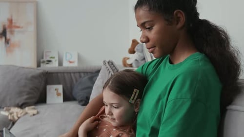 Young Nanny and Little Girl Watching Video on Digital Tablet