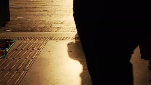 Пешеходное движение в городе на закате с силуэтами людей, отбрасывающих мечтательные тени на паву