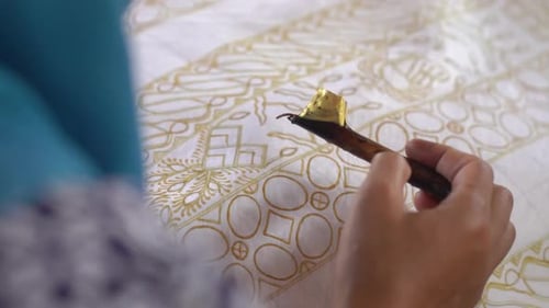 The technique of making hand-drawn batik using a canting tool. This craftsman is making batik typica