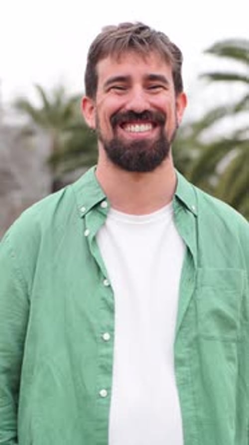 Smiling Bearded Man in Green Shirt Outdoors