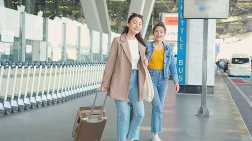 Passageira asiática de duas mulheres esperando um ônibus após sair do aeroporto.