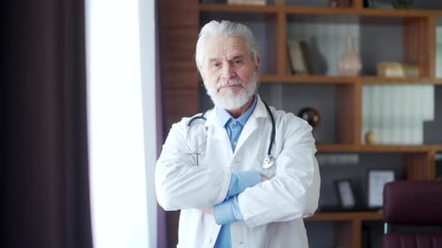 Portrait elder gray-haired experienced senior doctor standing in a modern hospital clinic in his