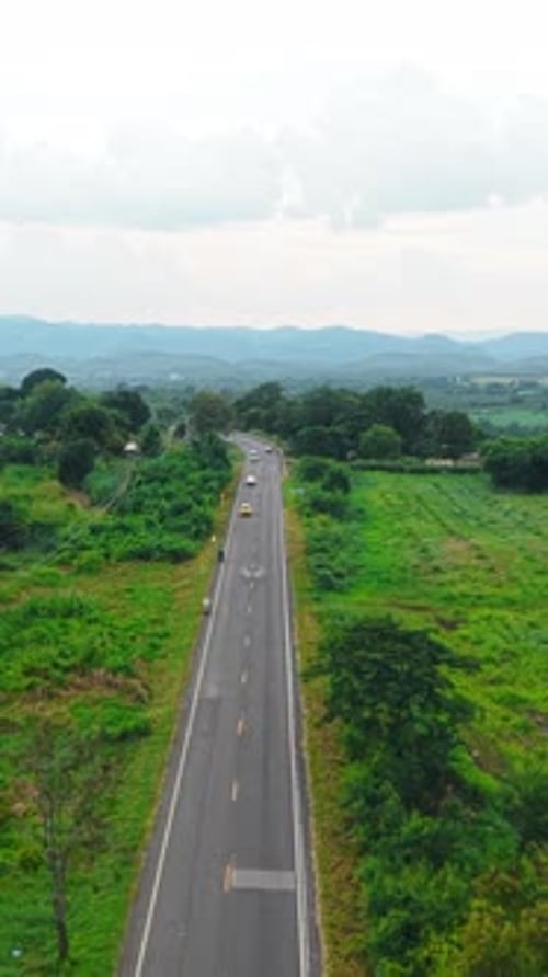 Vehicles Traveling on a Paved Road Through a Rural Landscape