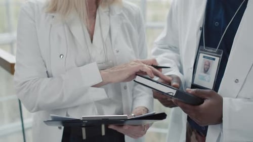 Unrecognizable Medical Workers Making Notes about Clinic Stuff in Document