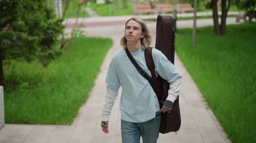 Musician on Walk Young Artist Heading to Performance Casual Musician Strolling Through Urban Park