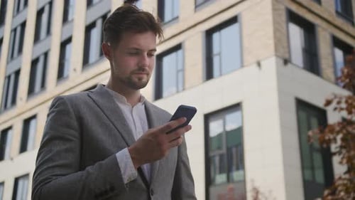 Businessman Using Smartphone Outdoors in Business District