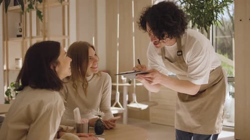 A Waiter Takes an Order From a Girls Who is Sitting at a Table in a Cafe A Beautiful Women in a Good