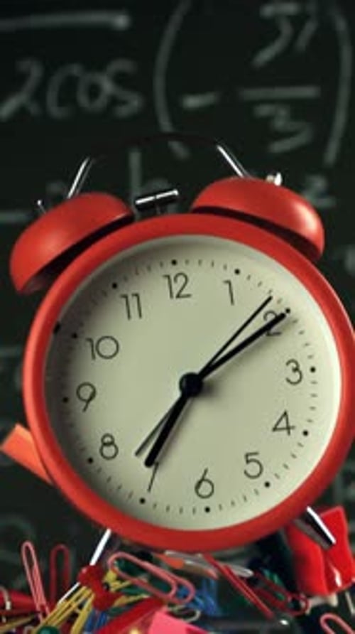 Alarm Clock and School Tools Soaring Up Against the Blackboard Background Filmed on a Highspeed