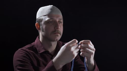 Man with prayer beads praying quietly in studio