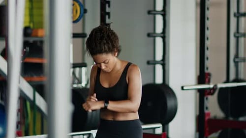 Woman Checks Smartwatch After Intense Gym Workout