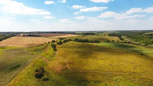 Green meadows, river, forests and wheat farmlands against blue sky.