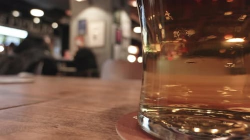 Nahaufnahme eines Bierglases auf einem Holztisch im geschäftigen Café