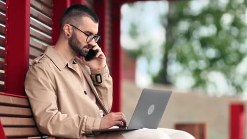 Modern Male Business Freelancer Man Working at Summer Park on Bench Use Laptop Talking Smartphone