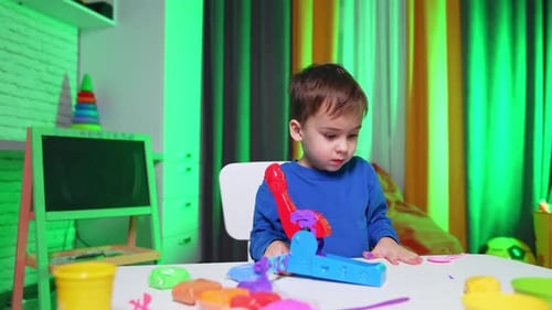 Smiling Boy Plays With Colorful Modeling Clay At Table