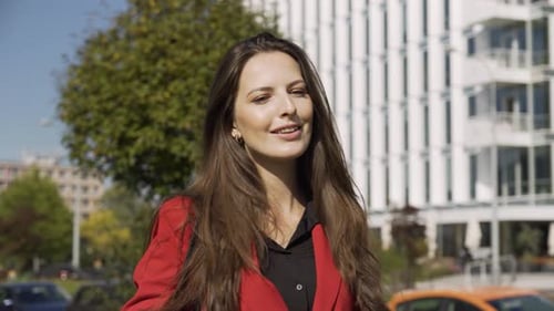 A Young Beautiful Caucasian Businesswoman Walks Down the Street with a Confident Smile