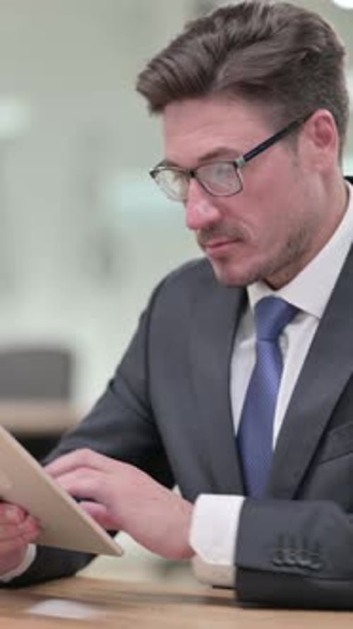 Serious Professional Middle Aged Businessman Using Tablet in Office, vertical video