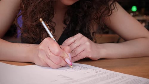 Woman Hand Filling Form on a Table