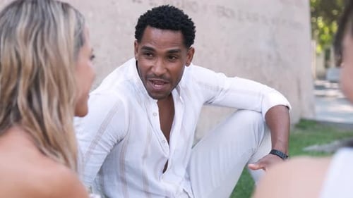 Diverse Friends Talking While Sitting Together at City Park