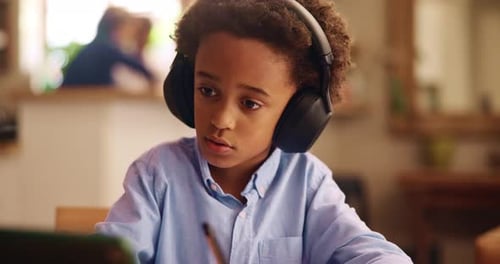 Boy with Headphones Doing Schoolwork on Tablet