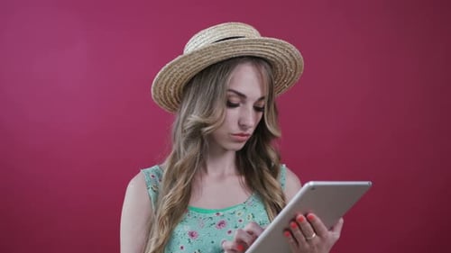 Beautiful Blonde Woman in a Casual Outfit Actively Using Tablet Then She Seriously Looks Straight to
