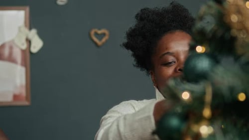 Cheerful Woman Decorating Christmas Tree in Cozy Home
