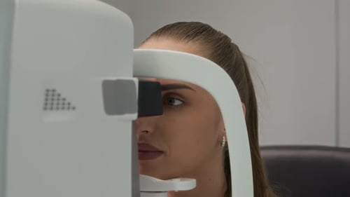 Patientin unterzieht sich einer Augenuntersuchung auf einem Diagnosegerät in der Optometrieklinik