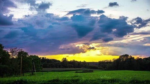 timelapse du coucher du soleil dans un champ rural verdoyant, prairie, nuages mouvants, time-lapse
