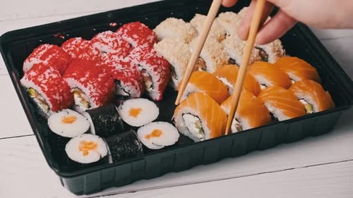 Sticks Take Sushi From the Plastic Sushi Box CloseUp