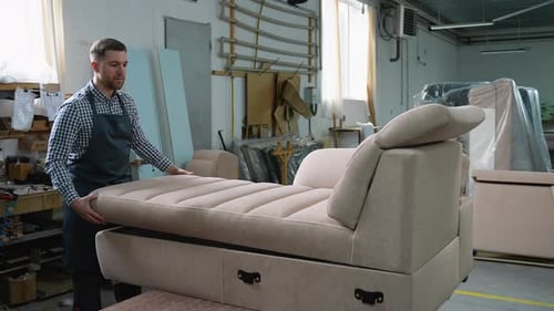 Ouvrier assemblant un canapé-lit avec compartiment de rangement