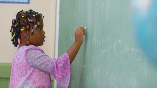 Student Writing On Chalkboard In School Classroom