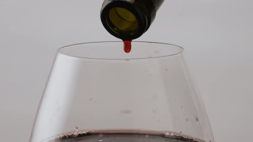 Köstlicher Rotwein tropft im Kelch aus der Flasche, Nahaufnahme. Gourmet-Rose