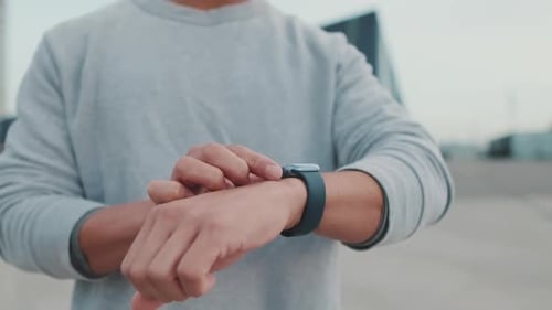 Close-up of hands, unrecognizable young man looking at smart watch