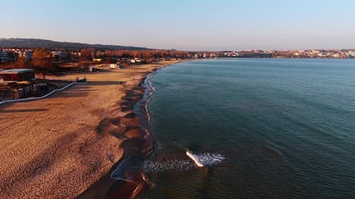 Quick rise over the line of water meeting land. Sandy shore of the sea from drone.