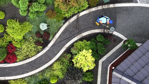 Caucasian Worker Cleaning Garden Path Using Pressure Washer