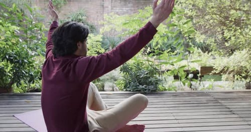 Caucasian man practicing yoga meditation on terrace in sunny nature, copy space, slow motion