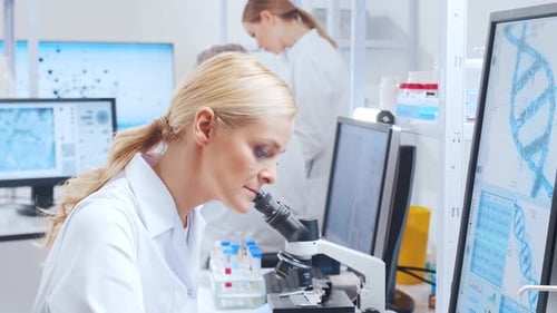 Woman Using Microscope in Bright Medical Laboratory