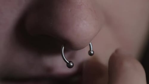 Niña que intenta quitarse la perforación en el tabique: plano de cerca