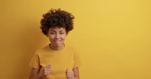 Enthusiastic woman dancing on a yellow backdrop